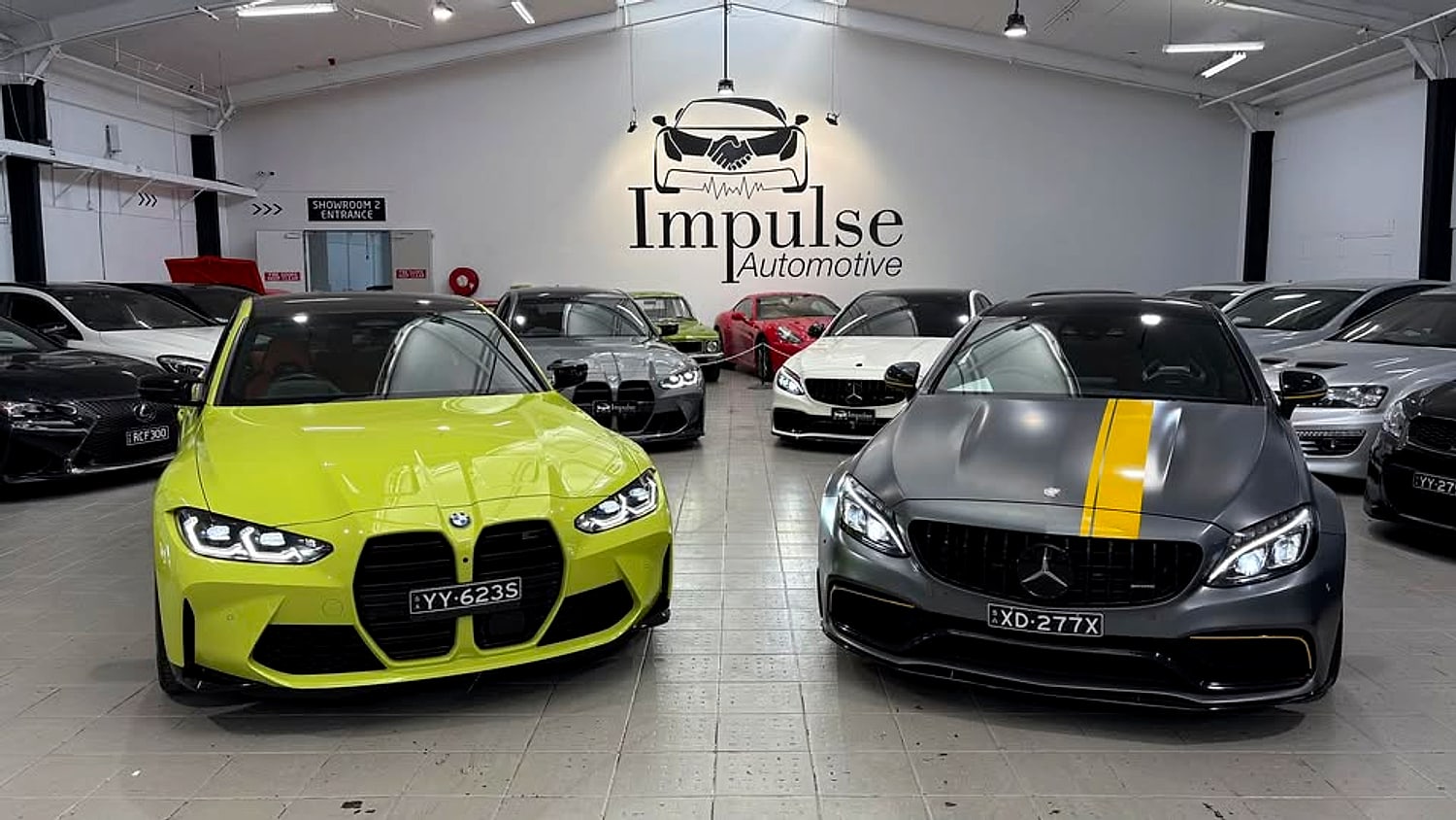 Cars lined up inside the Impulse Automotive showroom in Elizabeth South, led by a lime green BMW M and a black Mercedes-AMG